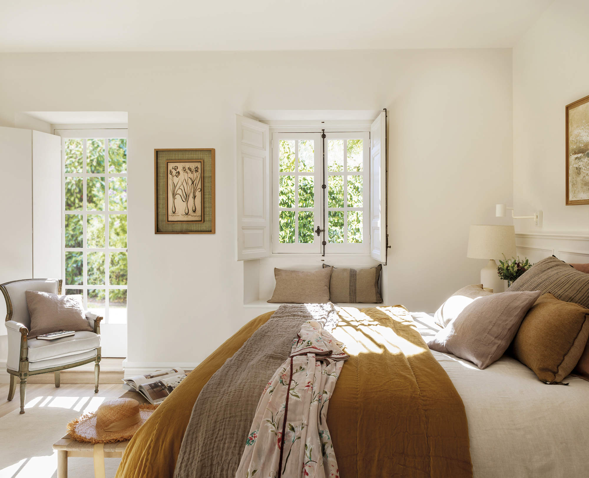 dormitorio blanco con cama con cojines mostaza y marrón, pared blanca